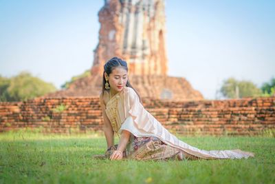 Woman sitting on grass against sky