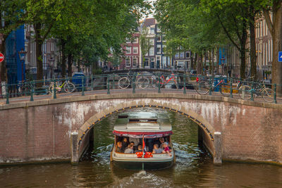 People in boat on bridge over canal in city