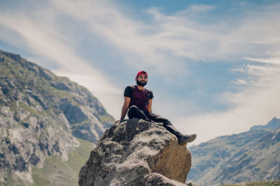 Low angle view of man climbing on mountain against sky