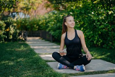 Full length of young woman sitting outdoors