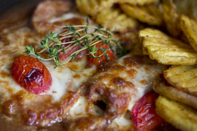Baked potatoes, tomatoes, pork with rosemary and yellow cheese, close up food