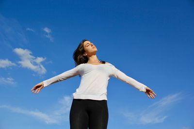 Low angle view of woman standing against blue sky