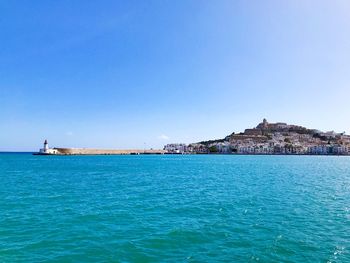 Scenic view of sea against buildings against clear blue sky