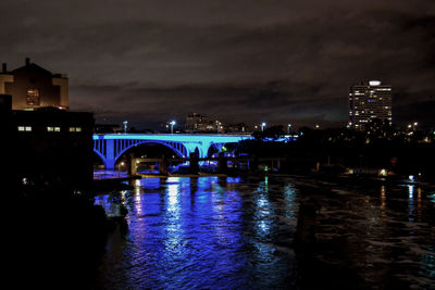 Illuminated bridge over river at night