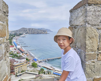 A young asian boy looking at the camera near the wall of an ancient fortress 