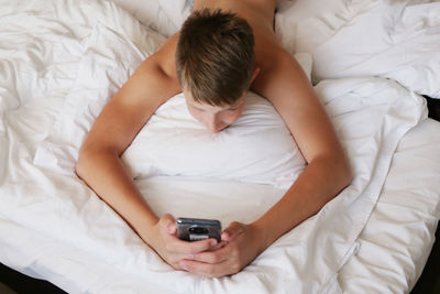 Man using phone while lying on bed at home