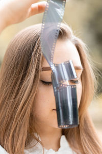 Close-up of young woman holding film reel outdoors