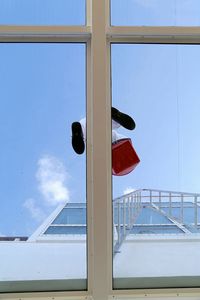 Window washer seen through window against sky