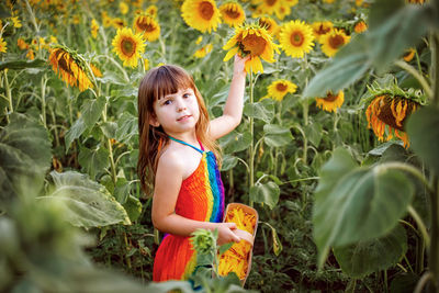 Portrait of cute girl standing on sunflower field