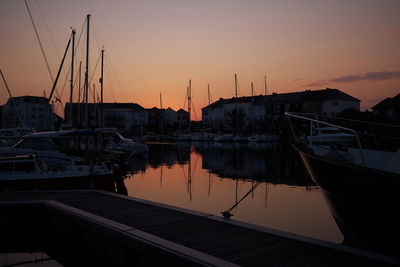 Boats moored at harbor during sunset