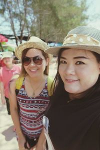 Close-up portrait of smiling friends wearing hats standing outdoors