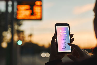 Woman buying ticket online near bus stop before ride. person paying for ticket using mobile payment