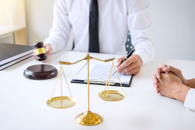 Midsection of lawyer sitting by client at office