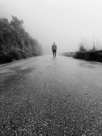Rear view of man walking on road during foggy weather