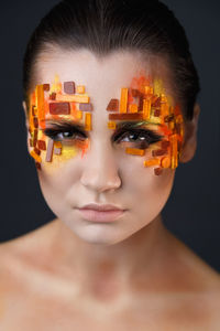 Portrait of woman with decorated face make-up against black background