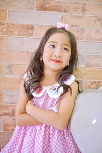 Portrait of girl standing against pink wall at home