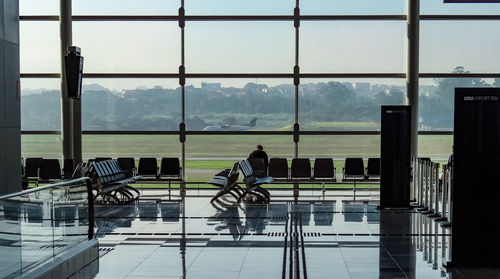 Man sitting at airport seen through glass window