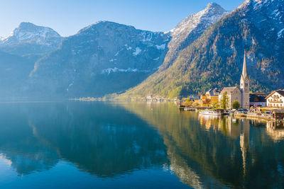 Scenic view of lake by buildings and mountains against sky