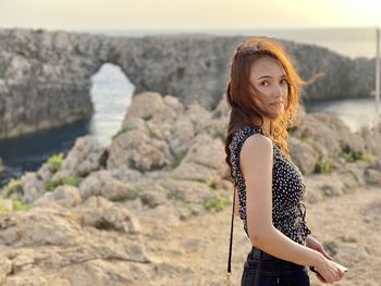 Portrait of young woman standing on rock at beach