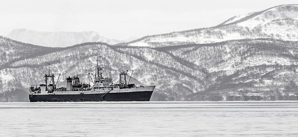 Large fishing vessel on the background of snow-covered hills and volcanoes