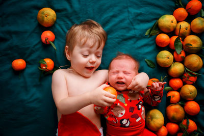 The older brother wants to feed the christmas newborn baby a tangerine, the baby cries.