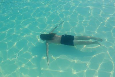 Rear view of young man swimming in pool