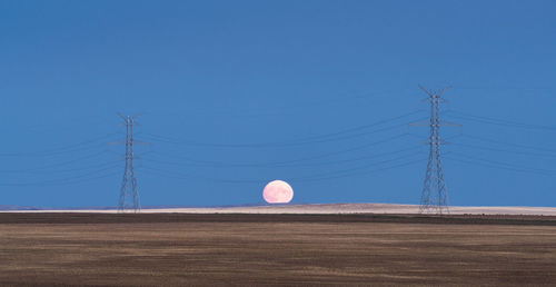 Electricity pylon on field against clear sky