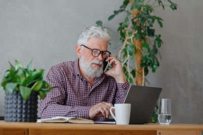 Young man using mobile phone while sitting on table