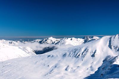 Scenic view of snow mountains against blue sky