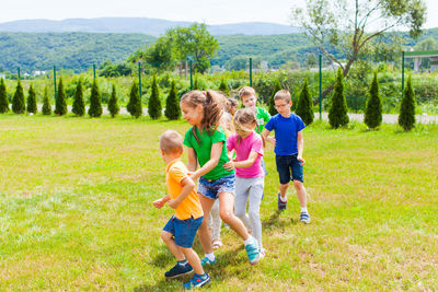 Rear view of people running on grass