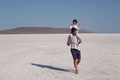 Son child on the neck of his father stand on a dried up salt lake in the crimea in the summer
