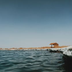 Hut on lakeshore against clear sky at atacama desert