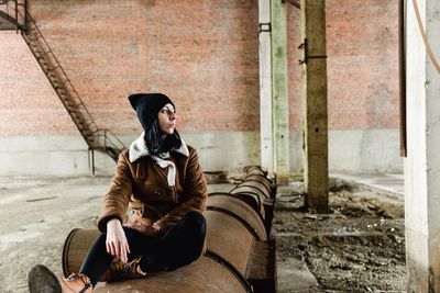 Full length of woman sitting on barrel