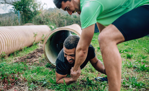 Man helping friend while exercising on land