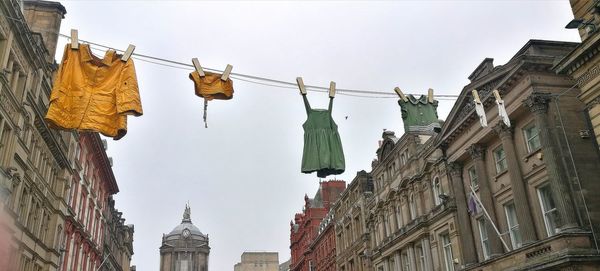 Low angle view of clothes hanging on building against sky