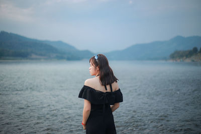 Young woman standing in sea against sky