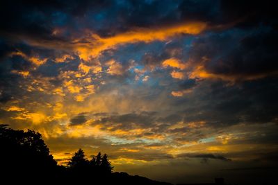 Silhouette of trees against cloudy sky