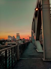 Bridge over river amidst buildings in city at sunset