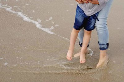 Low section of man standing on beach