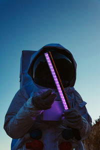 Low angle view of man wearing protective headwear against clear blue sky