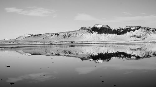 Scenic view of lake by snowcapped mountain against sky