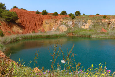 Scenic view of lake by rocks against sky