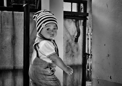 Side view portrait of baby boy standing by gate