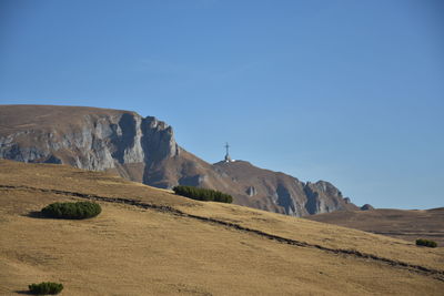 Scenic view of arid landscape against clear blue sky