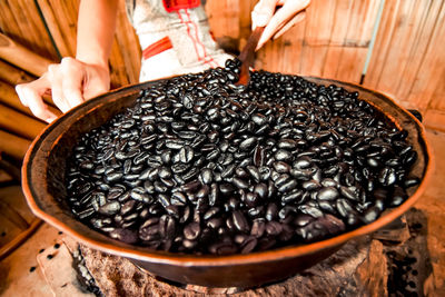 Close-up of woman holding coffee bean in bowl