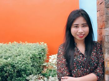 Portrait of smiling young woman standing against plants