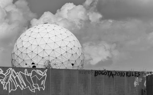 Graffiti on wall of tower against cloudy sky