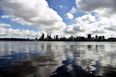 City at waterfront against cloudy sky