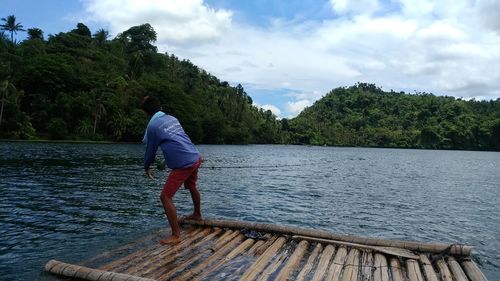 Full length of man standing on wooden raft in river