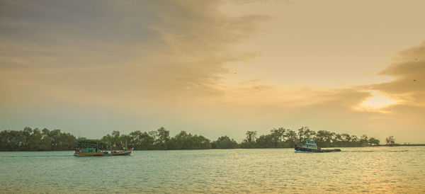 Boat sailing in sea against sky during sunset